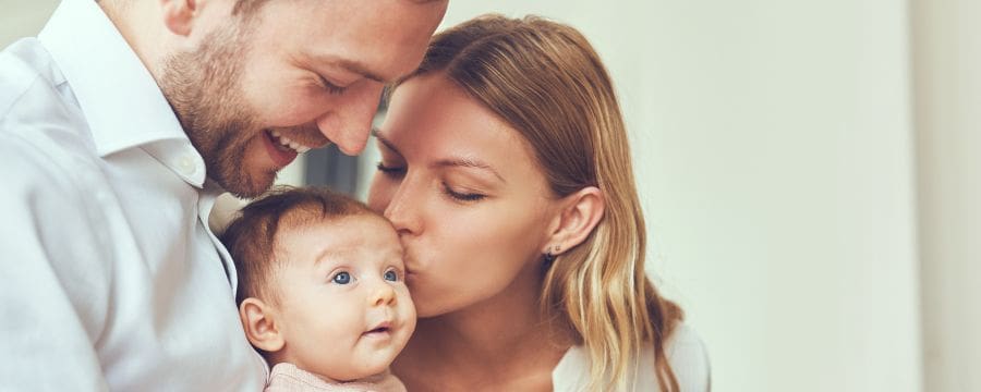 Smiling mother and father holding their newborn baby daughter at home