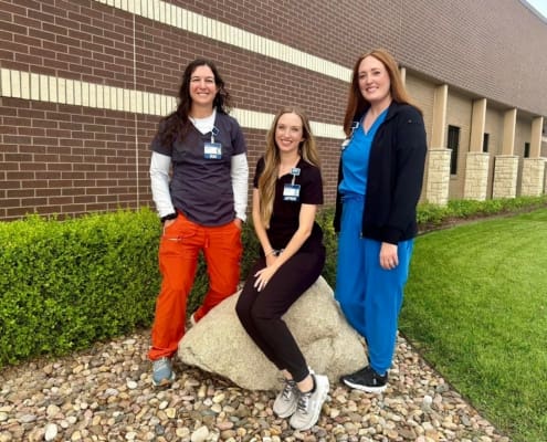 Three healthcare staff members in scrubs standing together outside Pawnee Valley Community Hospital
