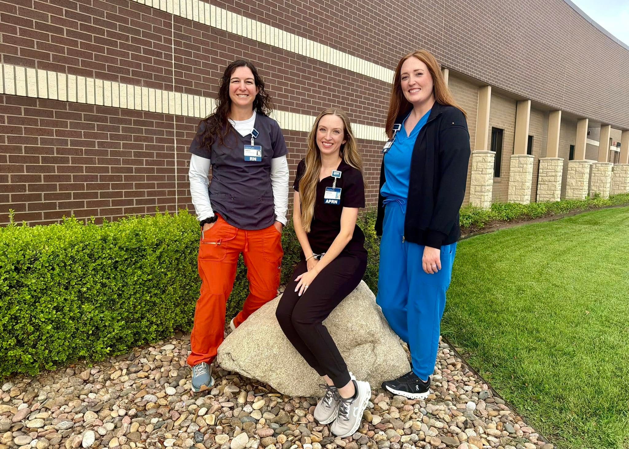 Three healthcare staff members in scrubs standing together outside Pawnee Valley Community Hospital